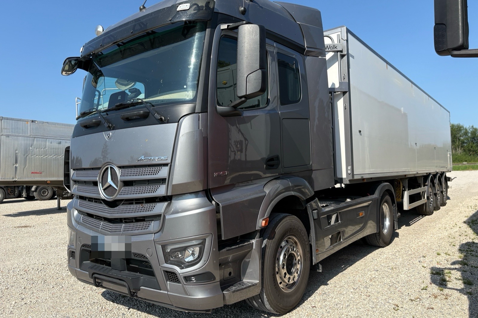 Grauer Lkw mit Sattelauflieger auf einem Kiesplatz