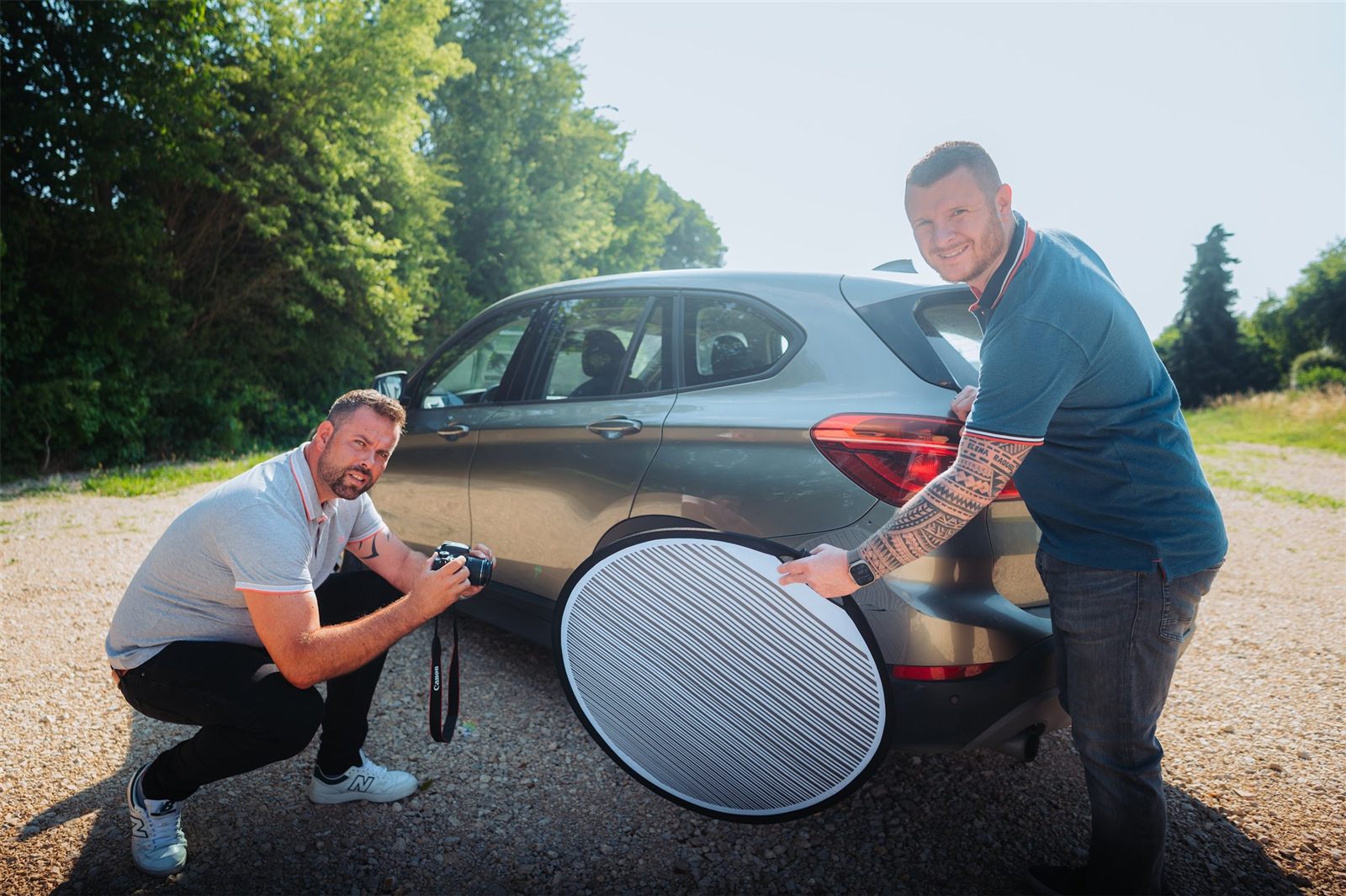 René Richter fotografiert ein beschädigtes Fahrzeug, Michael Lebelt hält dabei einen Reflektor – Fotodokumentation für ein Kfz-Gutachten