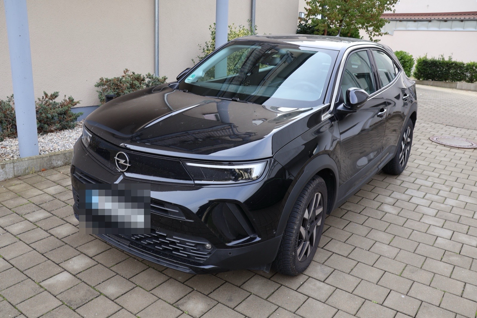 Schwarzes SUV auf einer gepflasterten Hofeinfahrt vor einem Wohnhaus
